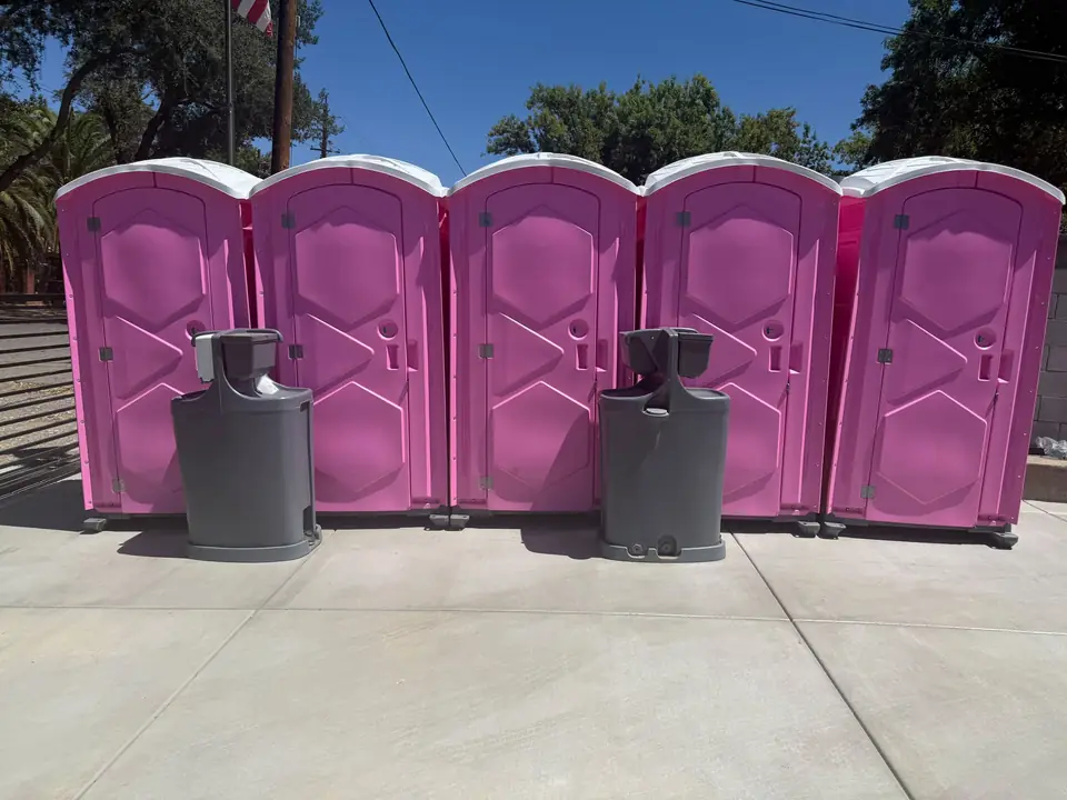 Row of pink event porta potties with hand-wash stations