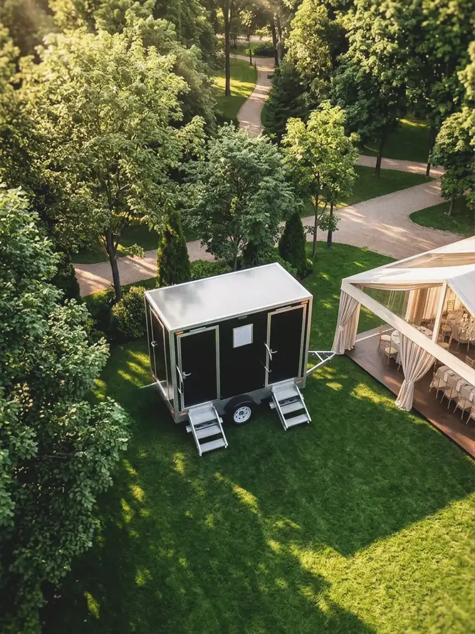 Restroom trailer on a lawn beside a garden wedding setup